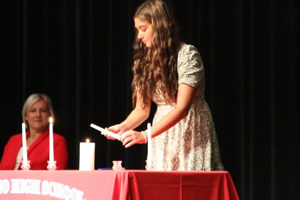 National Honor Society treasurer Halle Helmberger lights the candle representing character before speaking on the trait during Mondays NHS induction ceremony.