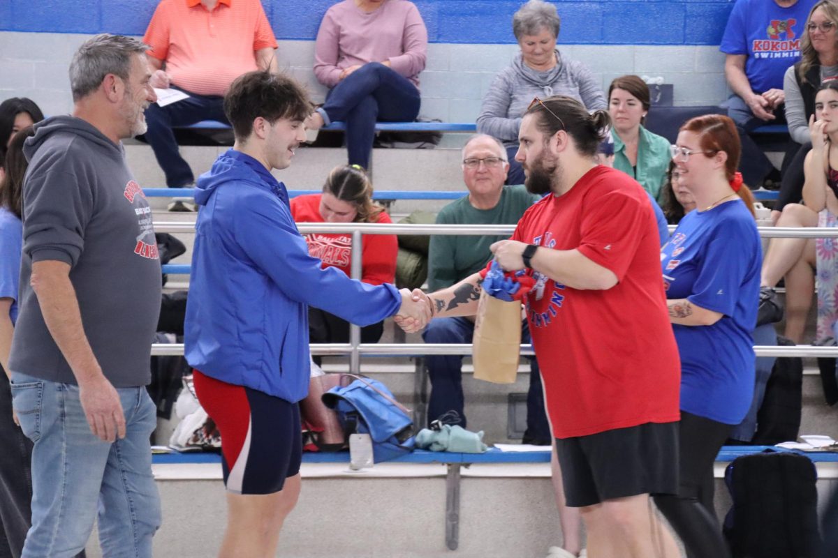 Head swim coach Zach Whiteman shakes hands with senior Isaac Flamino. Whiteman began teaching when the class of 2025 was in 6th grade.